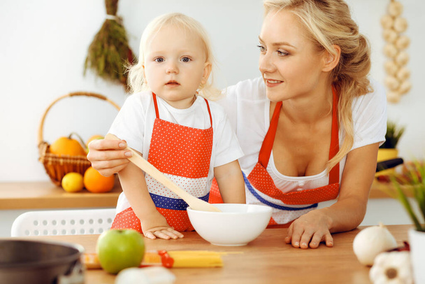 Happy mother and little daughter cooking in kitchen. Spending time all together, family fun concept - Zdjęcie, obraz