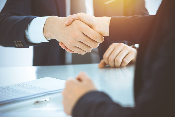 Gli uomini d'affari stringono la mano finendo di incontrarsi o negoziare in ufficio soleggiato. Concetti di business handshake e partnership - Foto, immagini