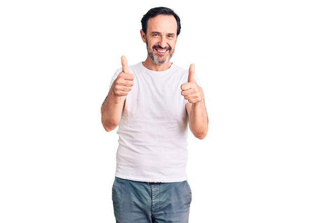 Hombre guapo de mediana edad con camiseta casual signo de éxito haciendo gesto positivo con la mano, pulgares hacia arriba sonriendo y feliz. expresión alegre y gesto ganador.  - Foto, Imagen