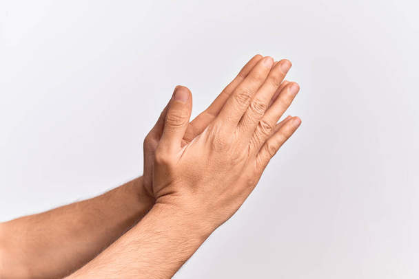 Mano di giovane caucasico che mostra le dita su uno sfondo bianco isolato che tocca le palme pregando con entrambe le mani insieme, simbolo religioso cattolico - Foto, immagini