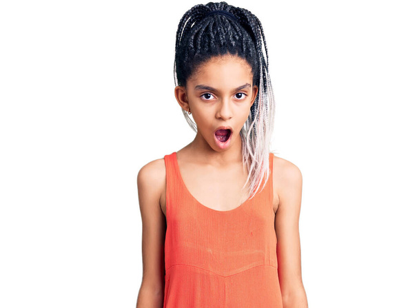 Mignon afro-américaine fille portant des vêtements décontractés dans le visage de choc, l'air sceptique et sarcastique, surpris avec la bouche ouverte  - Photo, image