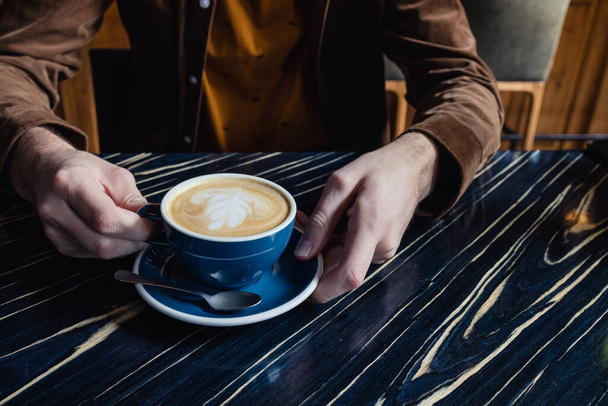 Close-up of man hand having a cup of cappuccino - Fotó, kép