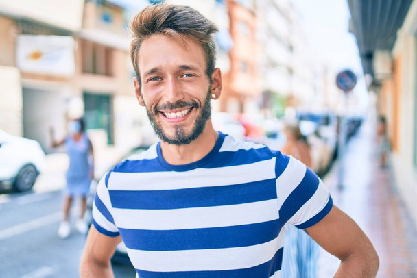 Knappe blanke man met baard glimlachen gelukkig buiten met behulp van smartphone - Foto, afbeelding