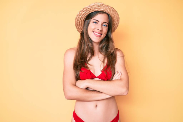 Hermosa mujer caucásica joven con bikini y sombrero cara feliz sonriendo con los brazos cruzados mirando a la cámara. persona positiva.  - Foto, Imagen