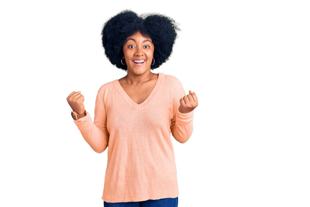 Niña afroamericana joven vestida con ropa casual celebrando sorprendida y sorprendida por el éxito con los brazos levantados y los ojos abiertos. concepto ganador.  - Foto, Imagen