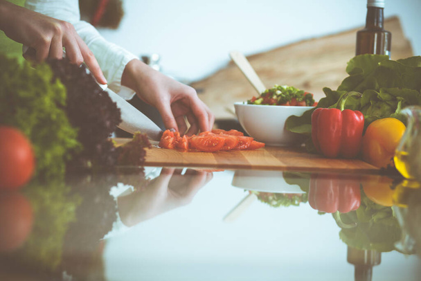 Unknown human hands cooking in kitchen. Woman slicing red tomatoes. Healthy meal, and vegetarian food concept - Foto, imagen