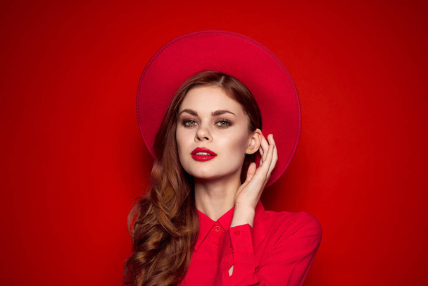 kobieta w czerwonej koszuli z jasnym makijażem i kapelusz na głowie emocje styl mody - Zdjęcie, obraz