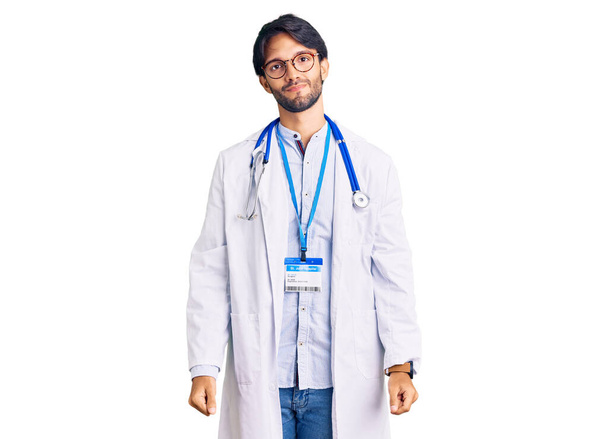 Handsome hispanic man wearing doctor uniform and stethoscope with serious expression on face. simple and natural looking at the camera.  - Fotoğraf, Görsel