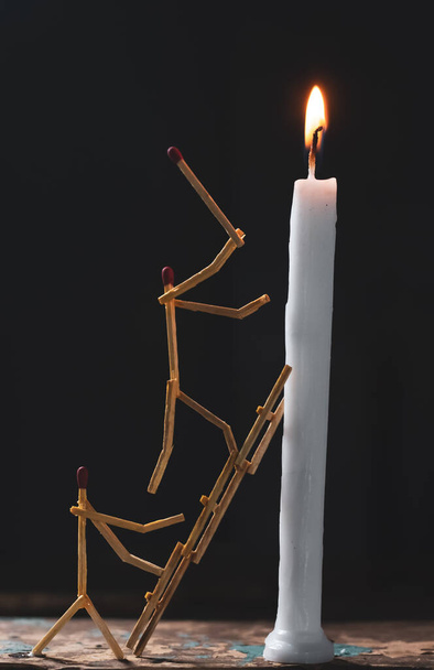 Matchsticks in form of a man lighting a candle, matchstick man lighting a candle. - 写真・画像