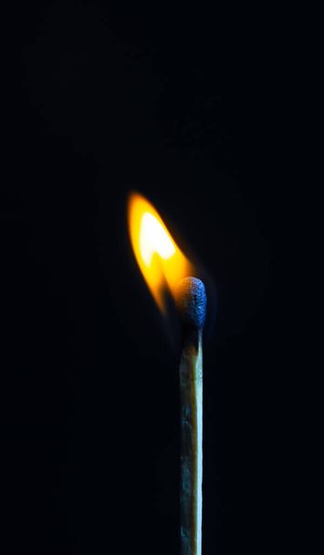 Single matchstick on fire in front of black background. - Photo, Image
