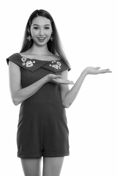 Studio shot of young beautiful Asian woman isolated against white background in black and white - Foto, Bild