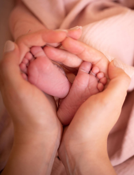 Babyfüße in den Händen der Mutter. Tiny Newborn Baby Füße auf weiblichen herzförmigen Händen Nahaufnahme. Mutter und ihr Kind. Happy Family Konzept. Schöne konzeptionelle Bild der Mutterschaft. Bild aus nächster Nähe. - Foto, Bild