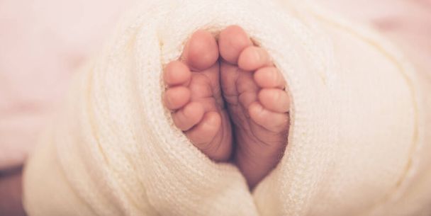 Kleine voet van pasgeboren baby. Zachte pasgeboren baby voeten tegen een roze deken. Kleine meisjes voeten met opgekrulde tenen. Afbeelding sluiten. - Foto, afbeelding
