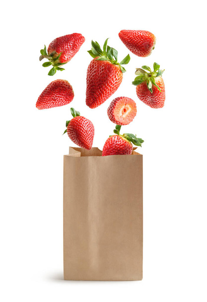 Flying strawberries, recyclable paper bag, isolated from the white background - Photo, Image