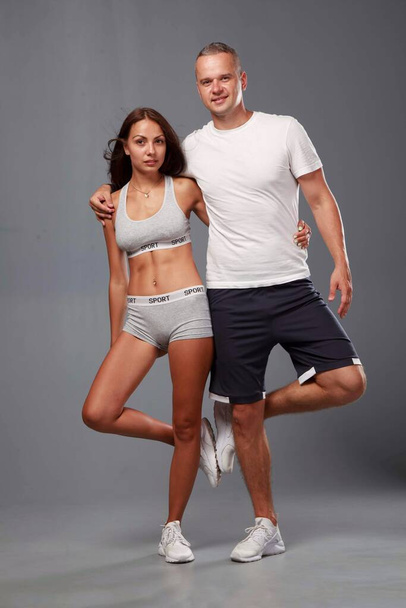Young sports couple engaged in fitness on a gray background - Foto, Bild