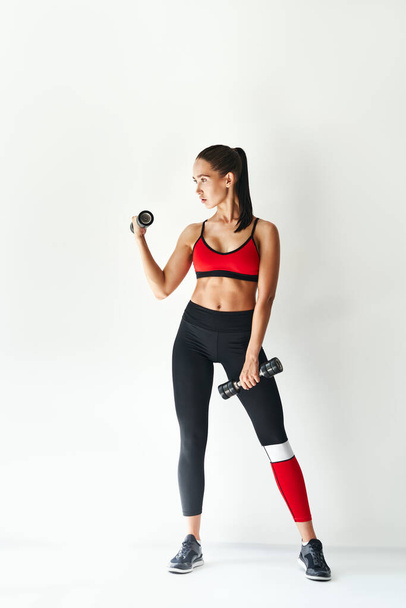 Sporty woman in sportswear doing exercise with dumbbells on white background. - Foto, Bild