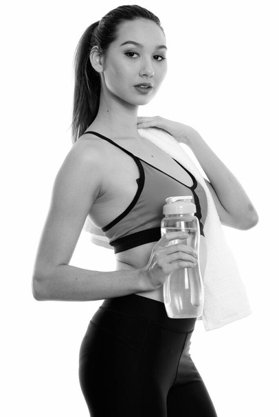 Studioaufnahme von jungen schönen asiatischen Frau bereit für das Fitness-Studio isoliert vor weißem Hintergrund in schwarz-weiß - Foto, Bild