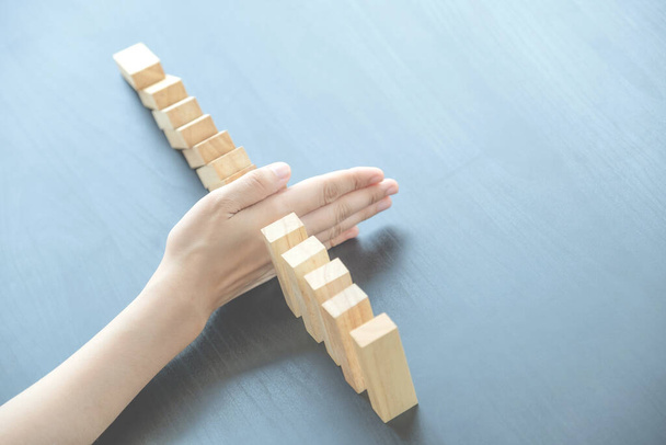 Vrouw hand te stoppen houten blokken voor de bescherming van andere houten blok, Concept Risico van beheer en strategisch plan. - Foto, afbeelding