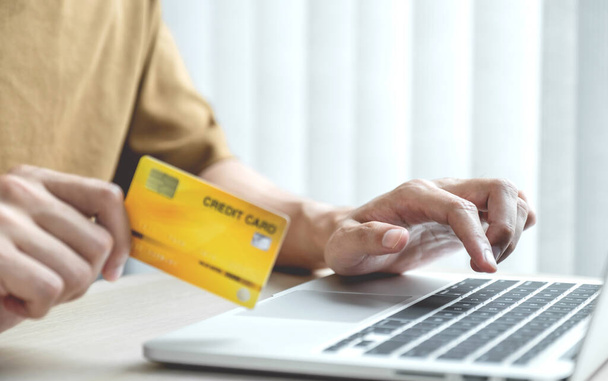 Biznesmen trzymać kartę kredytową do zakupów online na laptopie z domu, płatności e-commerce, bankowość internetowa, wydawanie pieniędzy. - Zdjęcie, obraz