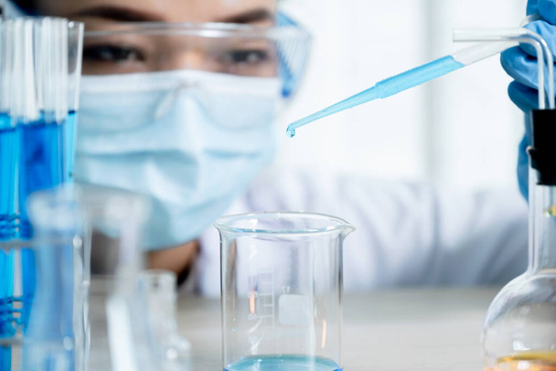 Scientists hold the pipette and drop the blue chemical liquid for research and analysis in a laboratory. - Photo, image