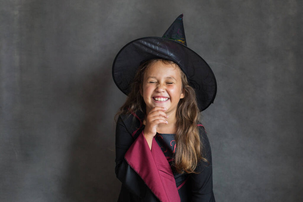 Happy girl in halloween witch costume on gray background  - Фото, зображення