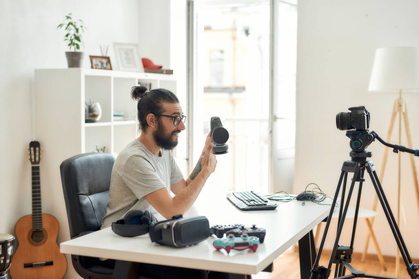 Чоловічий технологічний блогер тримає навушники, показуючи великі пальці вгору під час запису відео блогу або блогу про нові гаджети в домашній студії
 - Фото, зображення