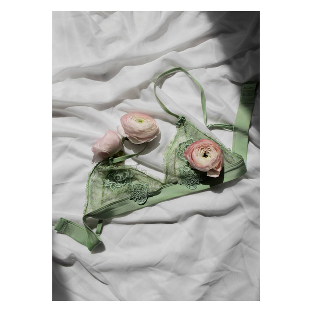 Pink ranunculus flower buds flat lay photo, green woman lace bralette on white background with fresh flowers feminine tender home decor - Photo, Image