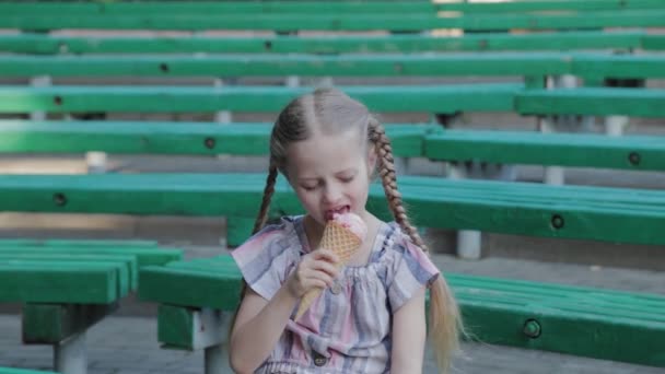 Όμορφη ευτυχισμένη κοπέλα τρώει παγωτό στο πάρκο σε ένα παγκάκι. - Πλάνα, βίντεο