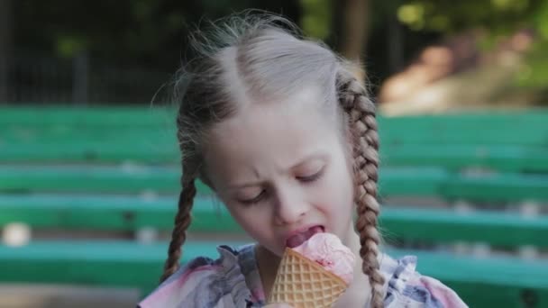 Krásná šťastná dívka jíst zmrzlinu v parku na lavičce. - Záběry, video