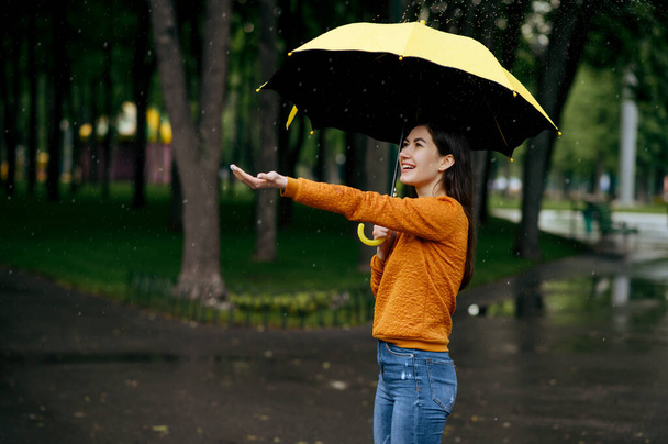 Az esernyős nő szereti az esőt a nyári parkban, esős napokon. Női személy egyedül sétál, nedves idő a sikátorban - Fotó, kép