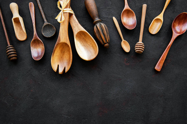 Top view on a wooden cutlery kitchen  ware on a  black stone background, flat lay - Photo, Image