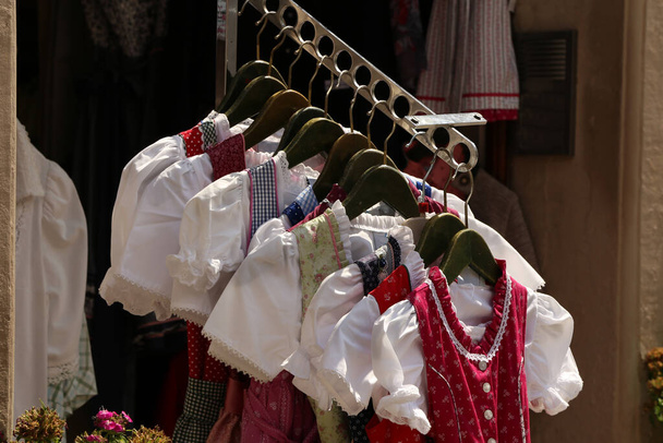 Dirndl φορέματα διαφόρων χρωμάτων κρέμονται μια σχάρα. Dirndl είναι ένα παραδοσιακό φόρεμα που φοριέται στην Αυστρία, Νότιο Τιρόλο, και τη Βαυαρία. - Φωτογραφία, εικόνα