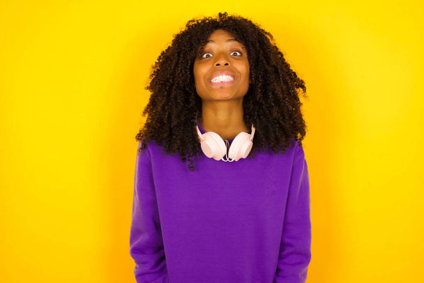 Afroamerikanerin lächelt wie verrückt auf gelbem Hintergrund. Emotionen und Gesten - Foto, Bild