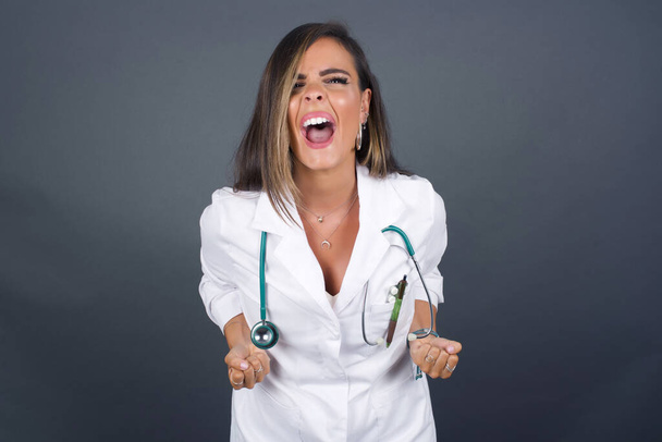 Close up portrait of doctor woman wearing medical uniform shouting with closed eyes - Photo, Image