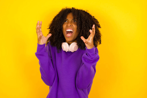 アフリカ系アメリカ人女性は黄色を背景に怒りを叫ぶ。感情やジェスチャーの概念 - 写真・画像