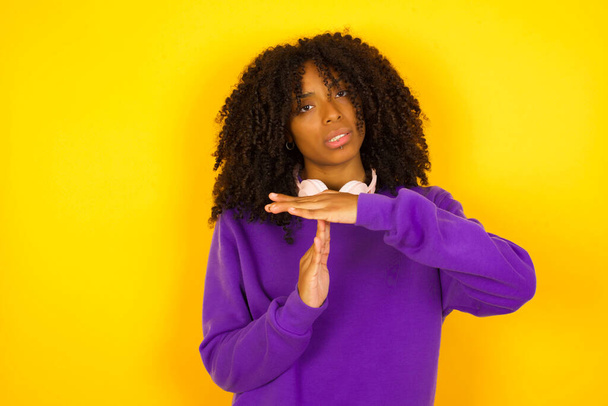 La donna afroamericana mostra un segno di gesto di stop su sfondo giallo. Emozioni e gesti concetto - Foto, immagini