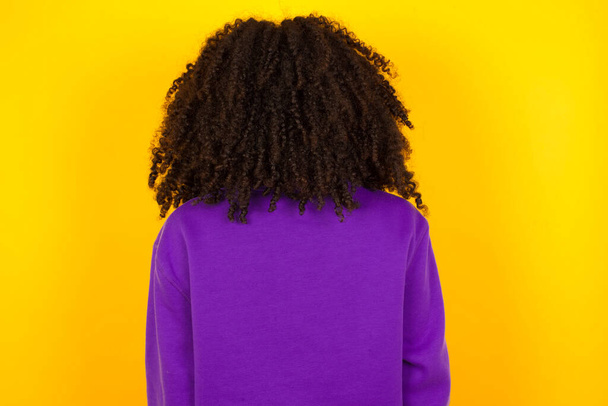 Femme afro-américaine vue de dos sur fond jaune. Concept d'émotions et de gestes - Photo, image