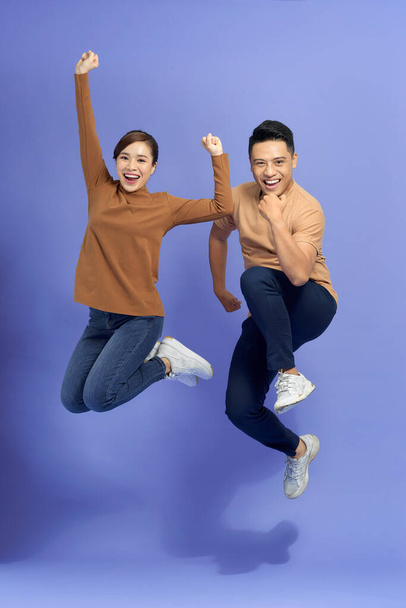 happy smiling couple isolated active jumping on purple background - Foto, immagini