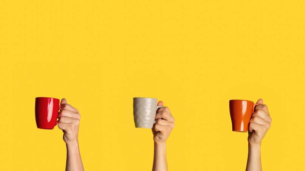 Collage with different mugs with hot beverages in male hands on orange background, empty space - Foto, Imagem