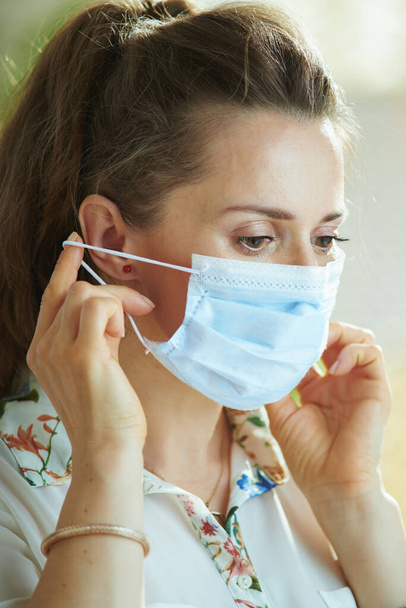 Life during coronavirus pandemic. young woman in white blouse wearing medical mask. - Foto, Imagem