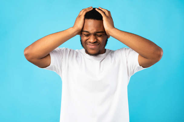 Musta mies kärsii päänsärky koskettava pää, sininen tausta - Valokuva, kuva