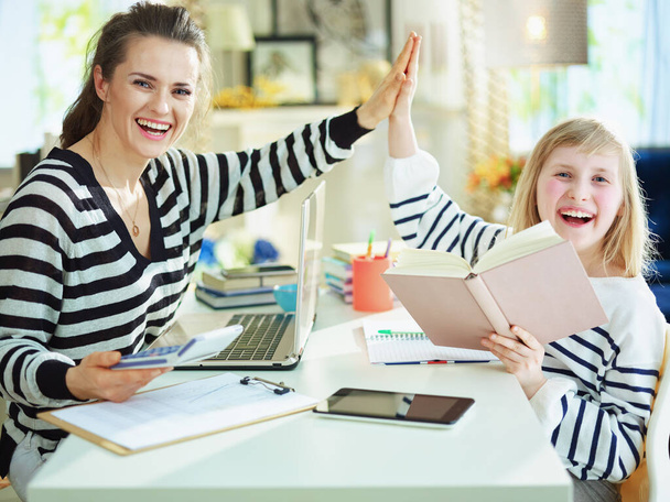 happy young mother and child in striped sweaters in home office in the modern house in sunny day high five. - Fotografie, Obrázek