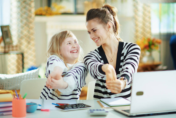 happy modern mother and daughter in striped sweaters in home office in the modern house in sunny day stretching. - Valokuva, kuva