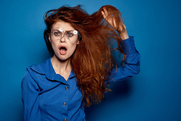 Energetica donna dai capelli rossi in camicia blu con occhiali gesticolando con le mani  - Foto, immagini