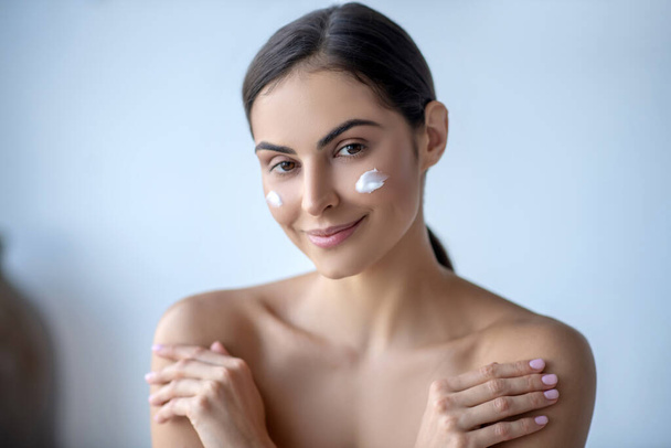 Cute woman with cream on her cheeks looking calm - Photo, image