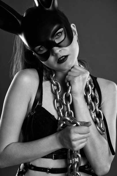 Sexy slender brunette in underwear and a black mask poses with metal chains - Foto, immagini