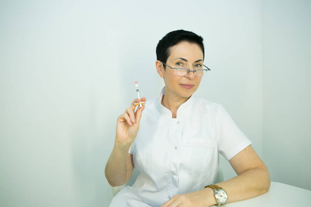 Δρ. κομεντολόγε. Μια γυναίκα ετοιμάζει μια σύριγγα με φαρμακευτική αγωγή για να διορθώσει τις ρυτίδες. - Φωτογραφία, εικόνα