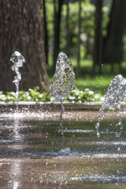 Water jet. City fountain. Water pressure. How to survive the heat. Hot summer in the city. Fountain splashes close up. Dancing fountains. Splashes shining in the sun. - Photo, image