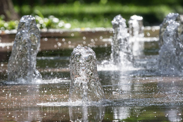 Water jet. City fountain. Water pressure. How to survive the heat. Hot summer in the city. Fountain splashes close up. Dancing fountains. Splashes shining in the sun. - Photo, Image