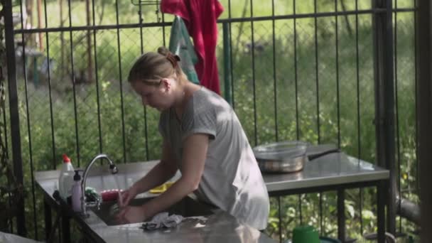 Mujer lavando con una esponja jabonosa un frasco de vidrio en la cocina, en casa de campo de verano - Metraje, vídeo